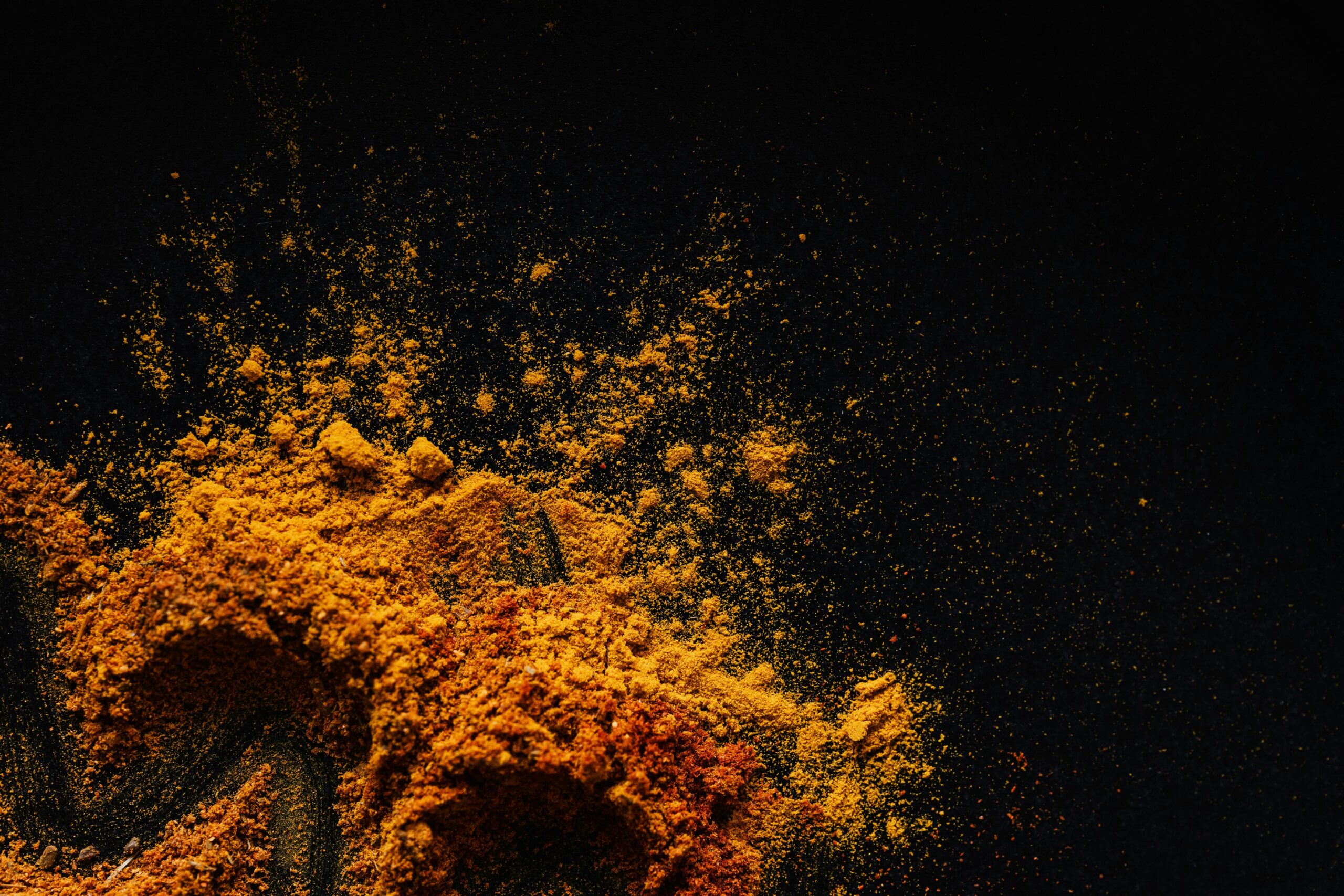 turmeric and other spices spilled on black background