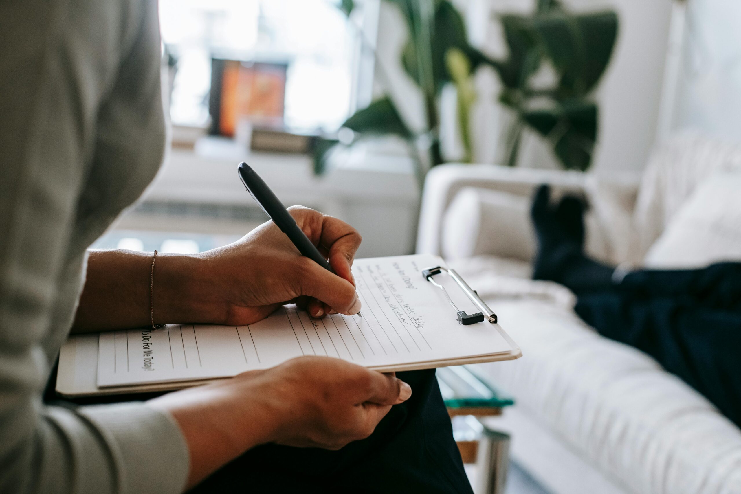 ethnic female therapist taking notes on clipboard